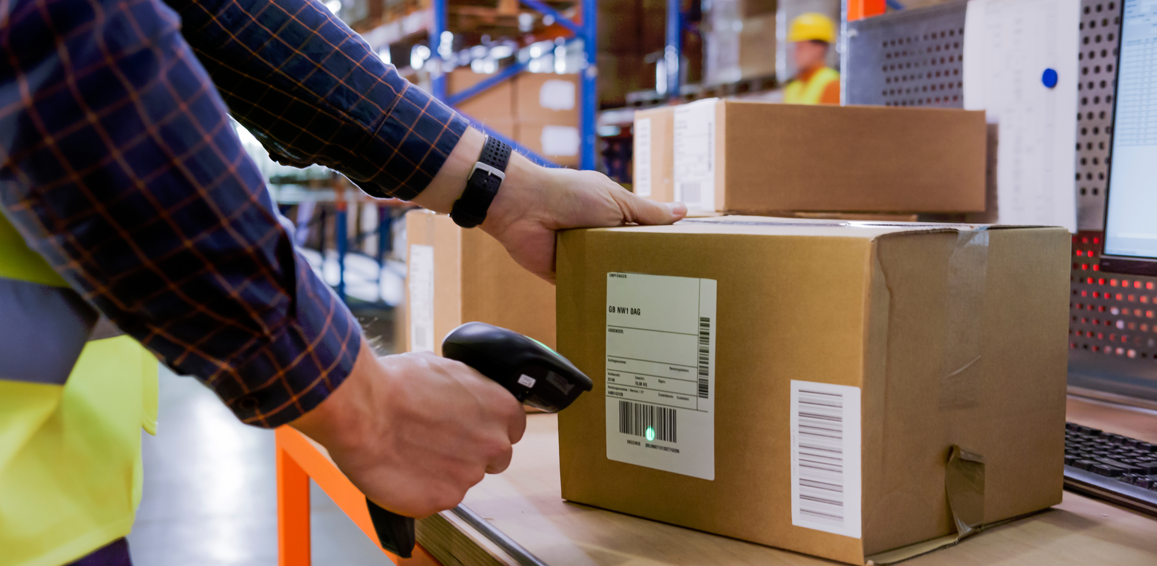 Male warehouse employee scanning packages on desk in warehouse with handheld scanner